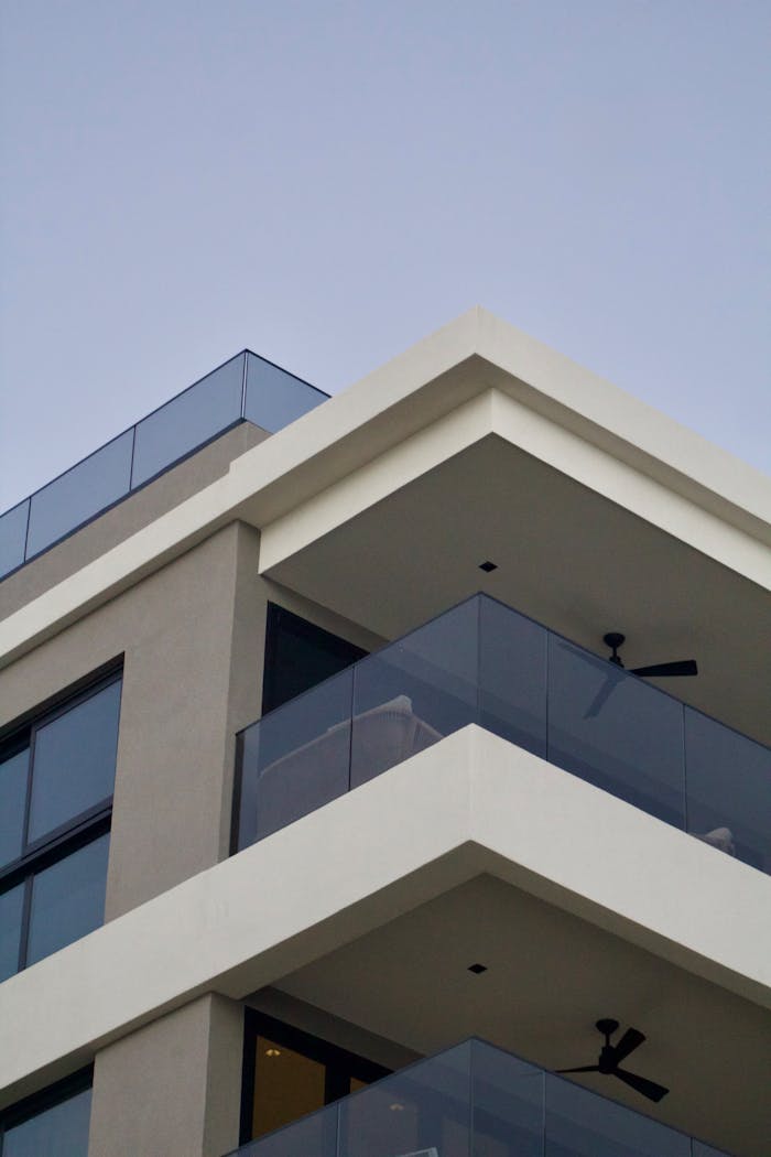 Contemporary apartment building with glass balconies against a clear sky.