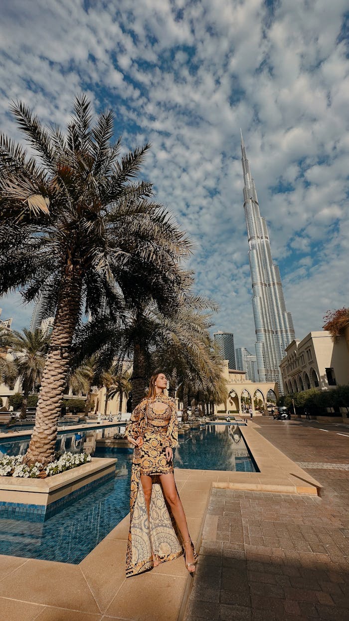Stylish woman poses with Burj Khalifa in the background under a vibrant sky.